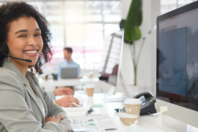 Mujer sonriente con auriculares en una oficina de atención telefónica